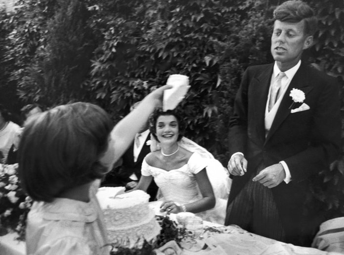 פרח girl Janet Auchincloss holds up a wedge of wedding cake for John F Kennedy 