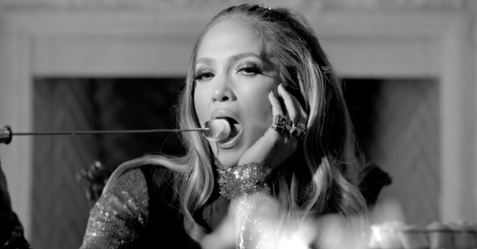 J. Lo roasts a marshmallow on a pile of burning money 